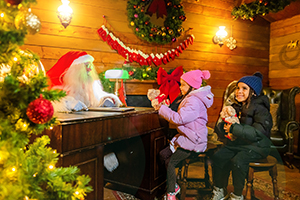 Image shows two excited visitors with Santa in his grotto at Alton Towers, Staffordshire